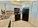 A compact kitchen featuring white cabinets, black appliances, and tile flooring at 2504 N Ocean Blvd. # 734, Myrtle Beach, SC 29577