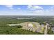 An aerial view of a community features homes surrounding a peaceful pond with wooded areas and a bright blue sky at 128 Caveson Way, Conway, SC 29526