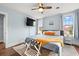 Bright bedroom featuring light blue walls, ceiling fan, TV, and bed with gray linens and orange pillows at 412 29Th Ave. N, Myrtle Beach, SC 29577
