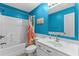 Bright bathroom with blue walls, white vanity, and tub with a shower at 6001 - N14 S Kings Hwy., Myrtle Beach, SC 29575