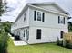 Shot of the back of a light green townhome, featuring white brick, black shutters, and well-maintained landscaping at 6306 Somerset Dr., Myrtle Beach, SC 29572