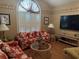Cozy living room with large arched window and shutters, with wood floor and tropical print sofa at 3517 Golf Ave., Little River, SC 29566