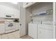 White washer and dryer in laundry room with shelves, next to a kitchen with white cabinets and appliances at 1100 Commons Blvd. # 104, Myrtle Beach, SC 29572