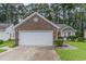 Home's attached garage and brick accents, surrounded by green lawns, mature trees, and shrubbery at 376 Mckendree Ln., Myrtle Beach, SC 29579