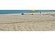 Sunny beach day with a yellow umbrella, beachgoers, and tire tracks in the sand at 2060 Cross Gate Blvd. # 305, Surfside Beach, SC 29575