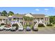 Exterior view of a two-story condo building with palm trees, white stairs and parking at 1137 Peace Pipe Ln. # 201, Myrtle Beach, SC 29579