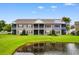 Rear exterior of condo building overlooking lush lawn and serene pond; Unit 201 highlighted at 1137 Peace Pipe Ln. # 201, Myrtle Beach, SC 29579