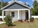 Charming single-story home with a covered front porch and freshly landscaped yard. Number 230 above the door at 230 Ashworth Dr., Tabor City, NC 28463