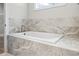 A bathtub is surrounded by marble tile with a window for natural light at 205 Waterfall Circle, Little River, SC 29566