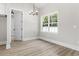 Neutral dining room with wood floor, elegant chandelier, and large window overlooking a wooded area at 205 Waterfall Circle, Little River, SC 29566