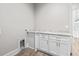 Bright laundry room boasts wood-look floors and white cabinets with a marble countertop, adding convenience and style at 205 Waterfall Circle, Little River, SC 29566
