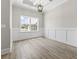 Living room featuring wood floor, large window, wainscoting, decorative ceiling, and elegant chandelier at 205 Waterfall Circle, Little River, SC 29566