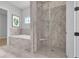 Modern bathroom featuring a walk-in shower, separate soaking tub and neutral-toned walls with marble-like accents at 289 Waterfall Circle, Little River, SC 29566