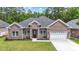 Charming brick home featuring a well-manicured lawn, two-car garage and a stylish, arched front door at 297 Waterfall Circle, Little River, SC 29566