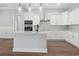 Bright kitchen boasts white cabinetry, stainless appliances, and an island with a sink at 297 Waterfall Circle, Little River, SC 29566