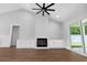 Open living space with hardwood floors, vaulted ceiling, a modern ceiling fan, fireplace, and sliding glass doors to the backyard at 297 Waterfall Circle, Little River, SC 29566