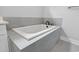 A built-in white bathtub with gray tiled surround, offering a modern and clean aesthetic at 309 Waterfall Circle, Little River, SC 29566