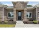 Close-up of a brick home's front entrance featuring a decorative glass door and manicured landscaping at 309 Waterfall Circle, Little River, SC 29566