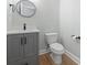 A modern powder room features a gray vanity, a toilet, and a round mirror at 9048 Abingdon Dr., Myrtle Beach, SC 29579