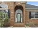 Inviting front entrance with a brick facade, arched doorway, and well-manicured landscaping at 9048 Abingdon Dr., Myrtle Beach, SC 29579
