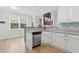 Partial kitchen view showing stainless dishwasher, white cabinets, gray counters, and breakfast area at 9048 Abingdon Dr., Myrtle Beach, SC 29579