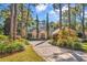 Charming brick home surrounded by lush trees with a patterned driveway leading to a grand entrance at 89 Gleneagle Ln., Pawleys Island, SC 29585