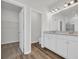 Bathroom featuring double sinks, white cabinetry, light wood flooring, and a door leading to the walk-in closet at 389 Sun Colony Blvd., Longs, SC 29568