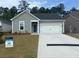 Charming one-story home featuring light green siding, a blue front door, and an attached two-car garage at 389 Sun Colony Blvd., Longs, SC 29568