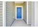 Inviting entryway showcasing a vibrant blue front door with white trim and light green siding at 389 Sun Colony Blvd., Longs, SC 29568