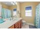 Well-lit bathroom features a vanity with a sink, toilet, and shower with daisy shower curtain at 237 Cloverleaf Dr., Longs, SC 29568