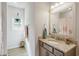 Bright bathroom featuring a vanity with granite countertop and grey cabinets, a large mirror and a hanging plant at 263 Red Maple Loop, Longs, SC 29568