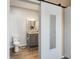 Bathroom featuring a toilet and vanity with granite countertop and grey cabinets, and a sliding barn door at 263 Red Maple Loop, Longs, SC 29568