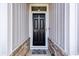A black front door with glass panels, a 'Welcome' mat, and stone accents along the home's facade at 263 Red Maple Loop, Longs, SC 29568