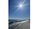 Scenic view of the beach with clear blue skies, gentle waves, and bright sunlight at 2511 Ye Olde Kings Hwy., North Myrtle Beach, SC 29582