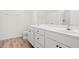 Bright bathroom featuring a double vanity, white cabinets, framed mirror, and wood-look flooring at 299 Hayloft Circle, Conway, SC 29526