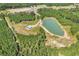 Areal view featuring a pond, building, and dirt road, all surrounded by lush trees and open fields at 7299 Cartrette Rd., Aynor, SC 29511