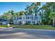 A front exterior view of the home showcasing its light-blue color and a well-manicured lawn with green shrubbery at 121 Grand Palm Ct., Myrtle Beach, SC 29579
