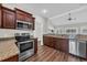 Modern kitchen with stainless steel appliances, granite countertops, dark wood cabinets, and an open layout to the living area at 2327 King Farm Rd., Aynor, SC 29511