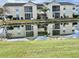 Scenic view of a two-story condo with a pond reflecting the facade and palm tree at 8830 Chandler Dr. # G, Surfside Beach, SC 29575
