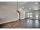 Spacious living room with vaulted ceiling, wood floors, modern lighting fixture, and a bright window view at 8667 Farrier Dr., Myrtle Beach, SC 29588