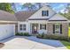 Beautiful home featuring a light exterior, side load garage, dark shutters, and manicured landscaping at 2588 Lake Vista Dr., Little River, SC 29566