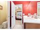 Bathroom vanity with an open door leading to a bedroom featuring a ceiling fan and a red and white patterned bedspread at 1066 Brentford Pl., Myrtle Beach, SC 29579