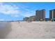 Expansive oceanfront beach with colorful umbrellas and people enjoying the sun and surf near a condo building at 5308 N Ocean Blvd. # 1014, Myrtle Beach, SC 29577
