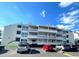Front view of a three-story building with several apartment units and parking in front at 1100 Possum Trot Rd. # F-215, North Myrtle Beach, SC 29582
