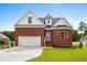 Charming red brick two-story home featuring an attached garage, front yard, and a beautifully landscaped entrance at 428 Meadow View Ct., Longs, SC 29568