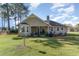 A well-maintained backyard with lush green grass, mature trees and the exterior of the home at 603 Bucks Trail, Longs, SC 29568