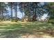 Lush green backyard with mature trees and glimpses of neighboring houses at 603 Bucks Trail, Longs, SC 29568