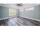 Empty bedroom showcasing gray walls, wood floors, and natural light from three windows at 1010 Club House Dr., North Myrtle Beach, SC 29582
