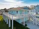 Elevated home with light blue exterior, spacious deck, and attached garage at 243 Calhoun Dr., Garden City Beach, SC 29576