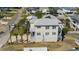 Aerial view featuring a multi-story beach house with a gray roof and palm trees, and flooded yard at 302A 32Nd Ave. N, North Myrtle Beach, SC 29582